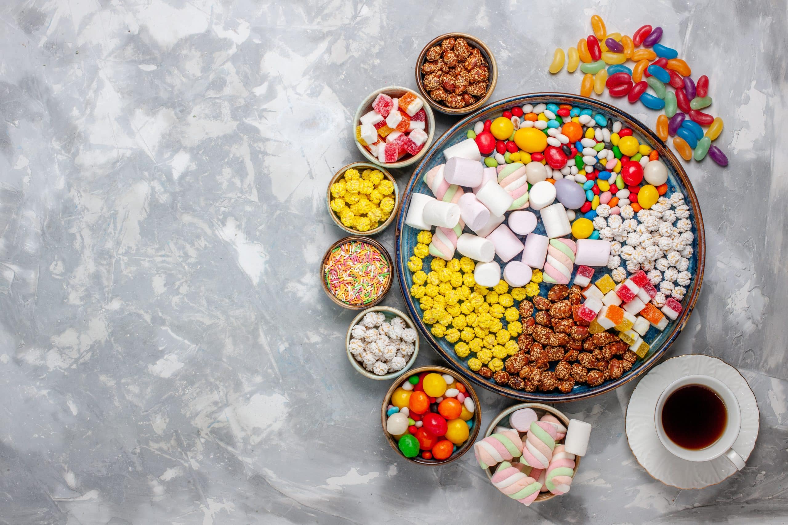 top-view-candy-composition-different-colored-candies-with-marshmallow-tea-white-desk-sugar-candy-bonbon-sweet-confitures